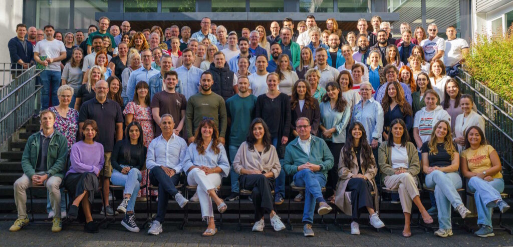 Gruppenaufnahme des Kollegiums der Gesamtschule Meiderich zu Beginn des Schuljahrs 2025/2026. In mehreren Reihen stehen die Lehrerinnen und Lehrer auf der Treppe vor dem Haupteingang der Schule und blicken in die Kamera.